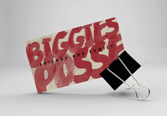 Eine schräg stehende Visitenkarte, die von einer schwarzen Vielzweckklemme gehalten wird. Auf der Karte steht in großen, roten Buchstaben im Graffiti-Stil „BIGGIES POSSE“, darüber liegt der kleinere schwarze Schriftzug „FRIENDS AND FAMILY“.