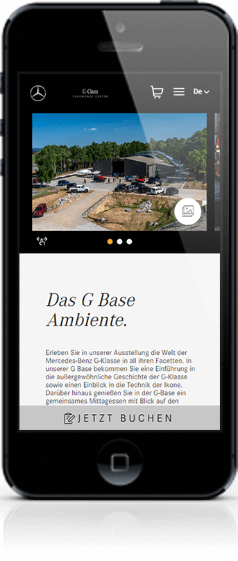 Smartphone-Display mit der mobilen Seite &bdquo;Das G Base Ambiente&ldquo;. Das obere Bild zeigt eine Au&szlig;enansicht des G-Class Experience Centers mit mehreren geparkten Gel&auml;ndewagen. Darunter folgen ein Einleitungstext zur Ausstellung und Geschichte der G-Klasse sowie ein grauer &bdquo;JETZT BUCHEN&ldquo;-Button.