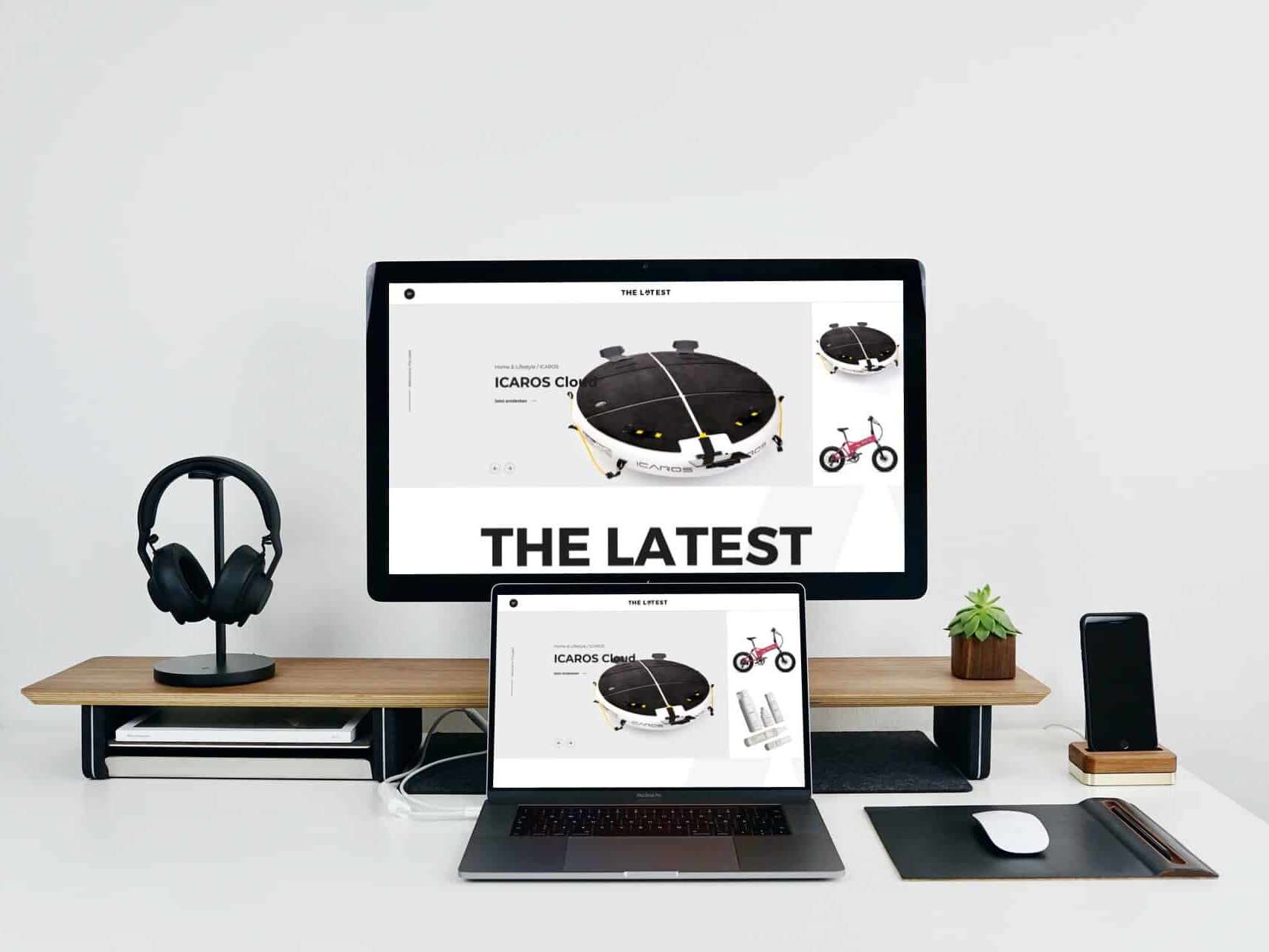 Mockup eines Schreibtischs auf dem ein Monitor, ein , ein Laptop, ein Smartphone, Over-Ear-Kopfhörer und eine Maus stehen. Gezeigt wird auf den Monitoren The Latest.
