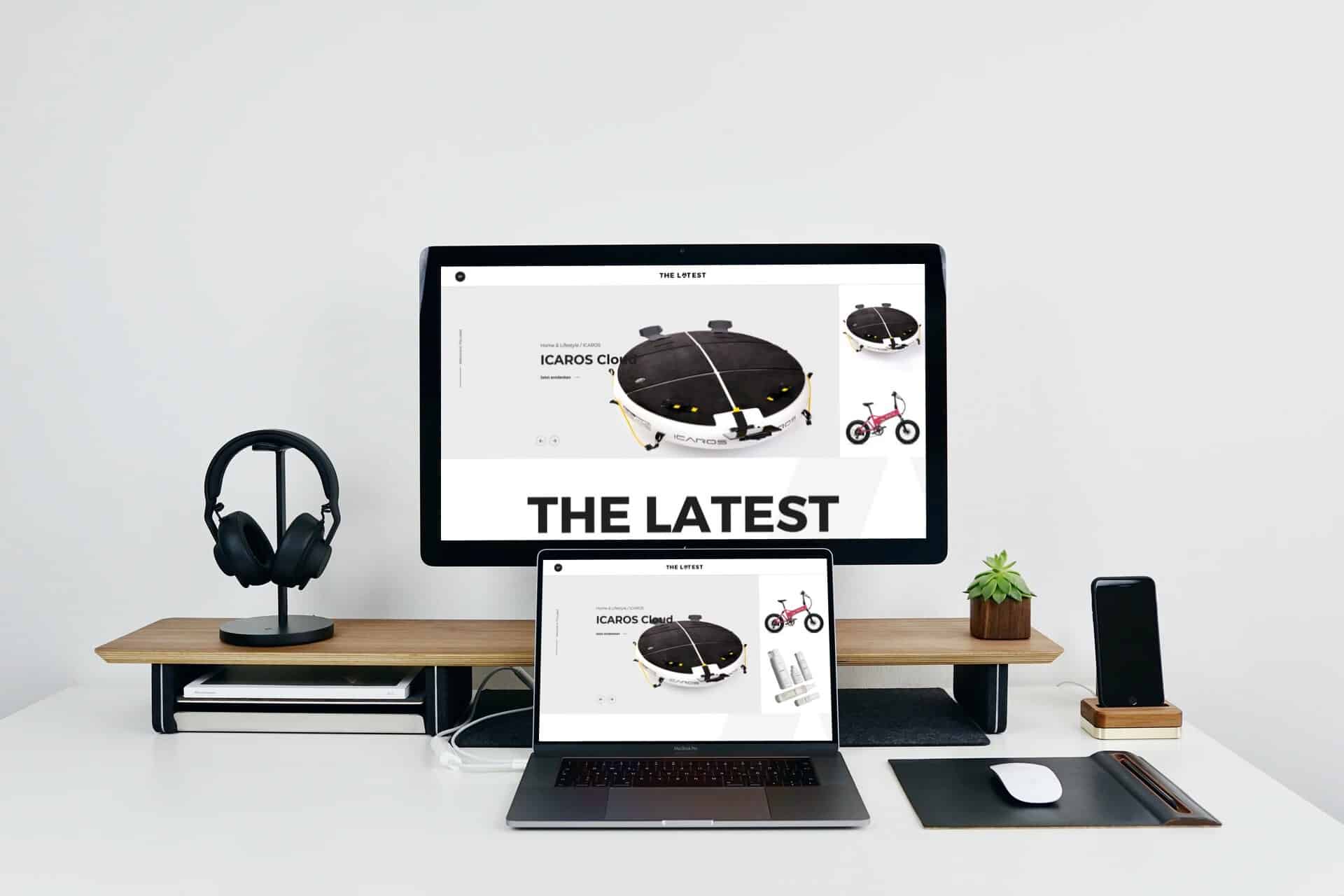 Mockup eines Schreibtischs auf dem ein Monitor, ein , ein Laptop, ein Smartphone, Over-Ear-Kopfhörer und eine Maus stehen. Gezeigt wird auf den Monitoren The Latest.
