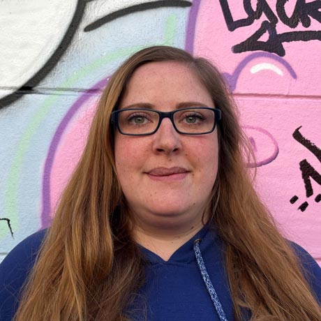 Portrait von Ulrike Seilz, Mitarbeiterin von Knorke Media. Sie trägt einen blauen Pullover und eine dunkle Brille.