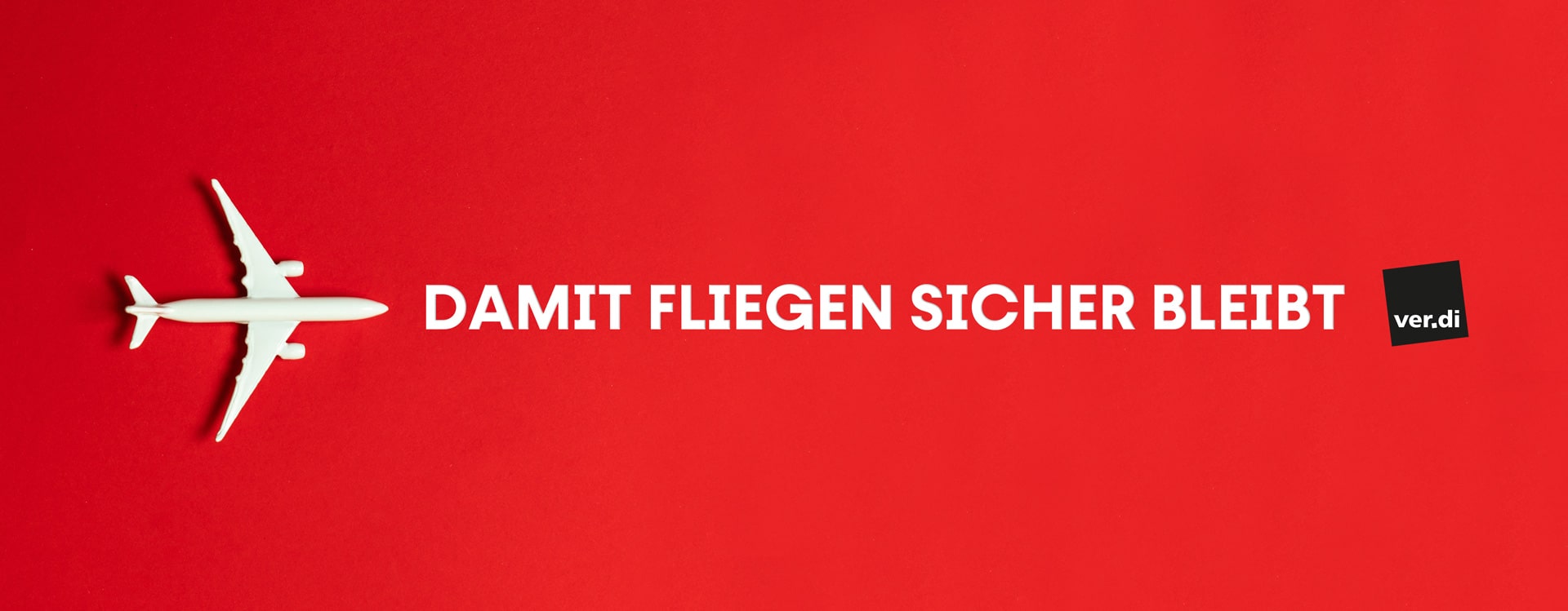 Ein wei&szlig;es Modellflugzeug fliegt auf rotem Hintergrund von links nach rechts. Daneben steht der wei&szlig;e Slogan &bdquo;DAMIT FLIEGEN SICHER BLEIBT&ldquo;, gefolgt vom schwarzen ver.di-Logo am rechten Rand.